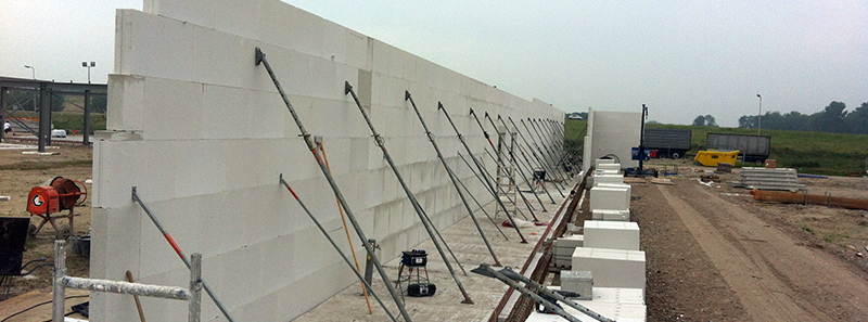 Hoge kalkzandsteen wand met schoren tijdens de bouw